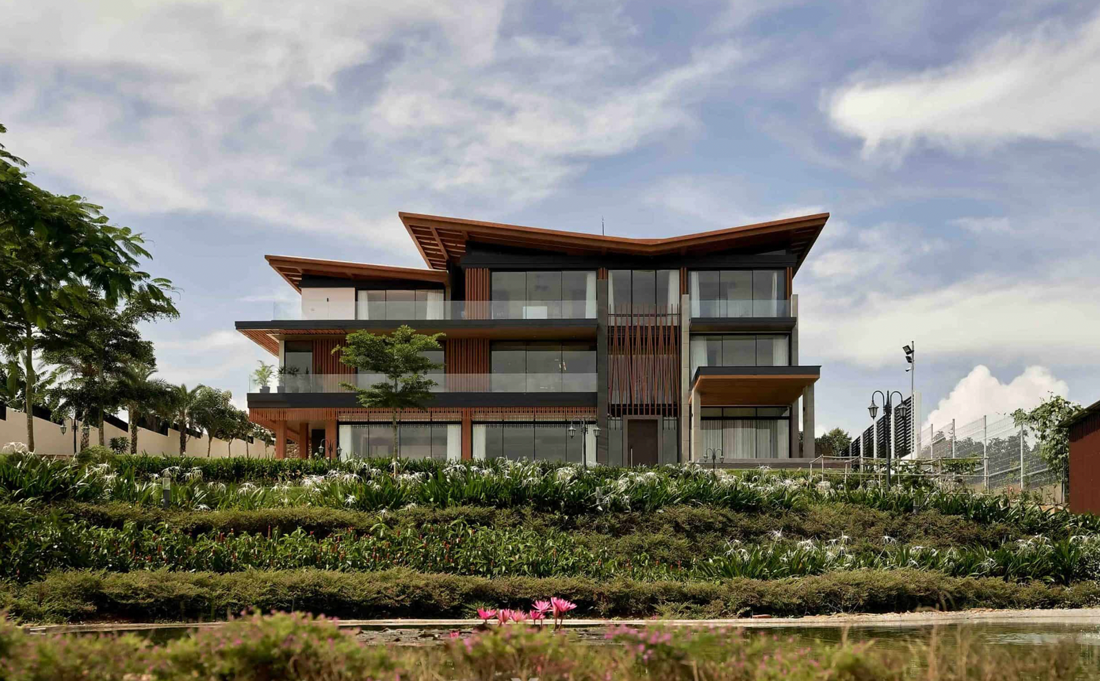 Biệt thự hiện đại với vườn cây xanh, trời xanh và mây trắng.