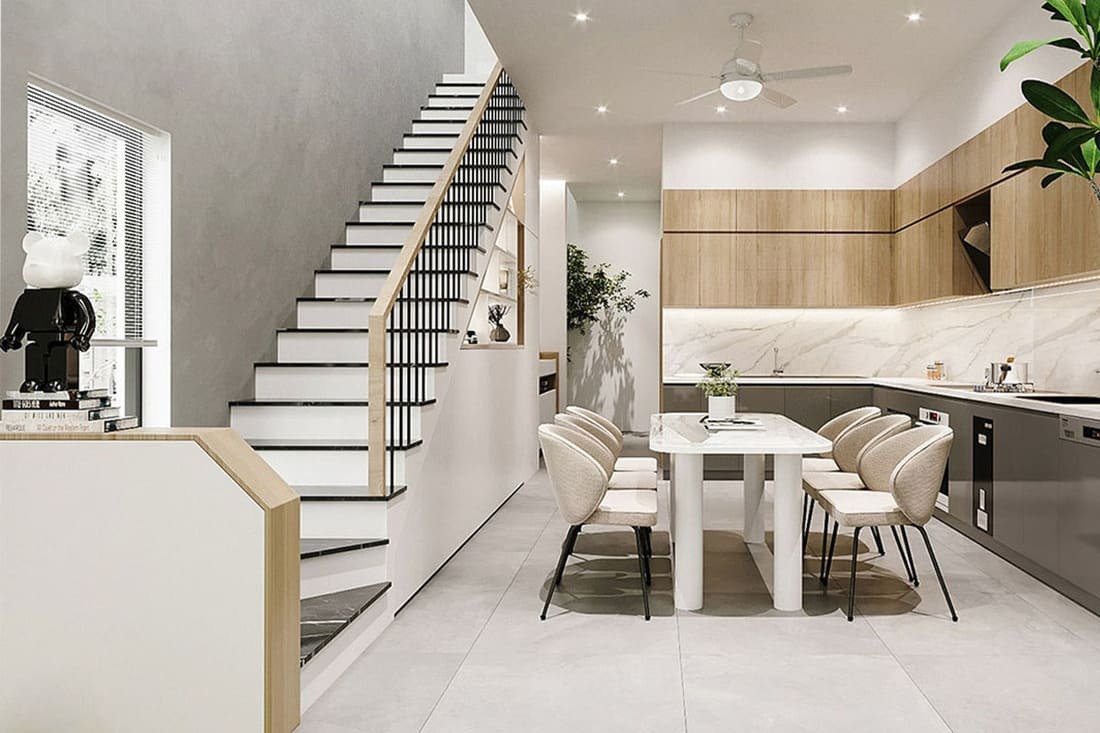 Nhà bếp hiện đại, bàn ăn với ghế bọc êm, cầu thang bên cạnh, ánh sáng tự nhiên chiếu sáng.