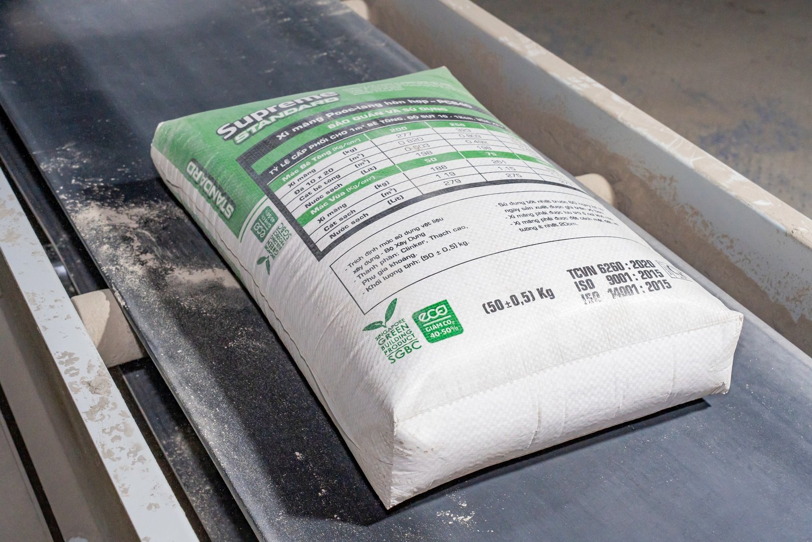 mot-so-luu-y-khi-lua-chon-xi-mang-2 Túi xi măng trên băng chuyền sản xuất, nhãn hiệu và thông số kỹ thuật rõ ràng.