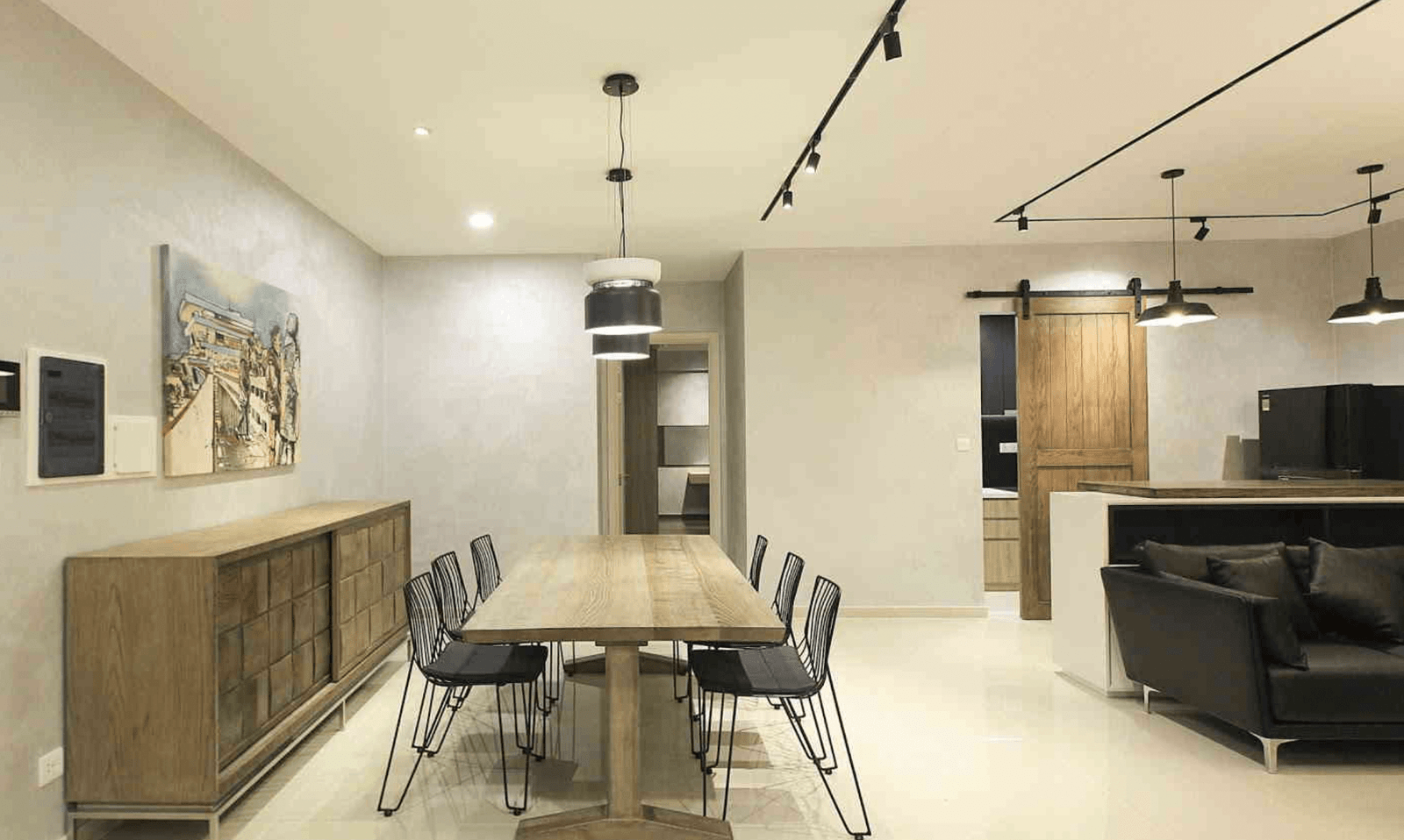 Phòng ăn hiện đại với bàn gỗ dài, ghế đen và đèn treo phong cách công nghiệp trong không gian tối giản.